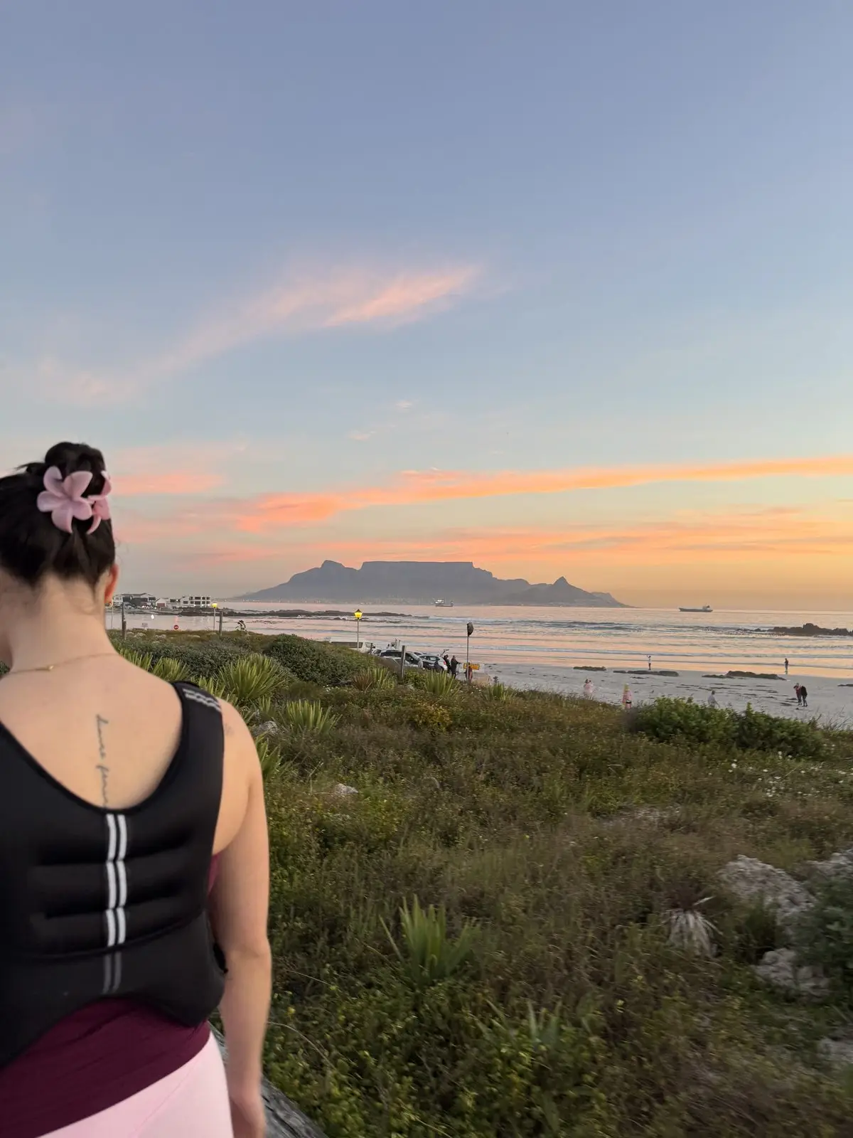 A woman looking out over the dunes to Table Mountain at sunset