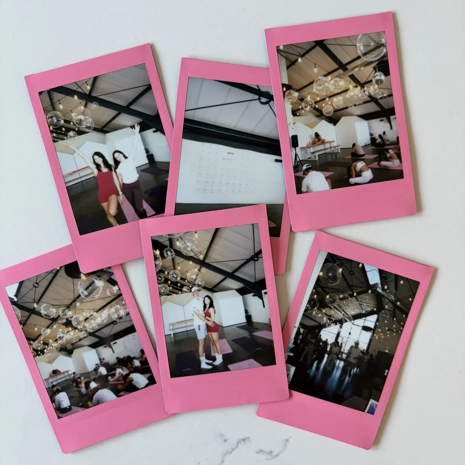 Pink instant photos from a Bloom morning laid out on marble